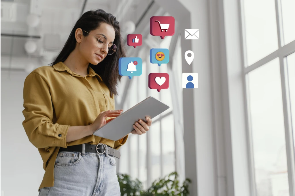 A woman in a mustard-colored shirt uses a tablet near a bright window with floating social media notification icons.